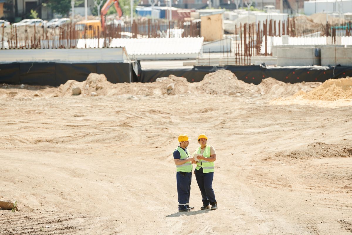 Two site engineers in hard hats on a cleared construction site